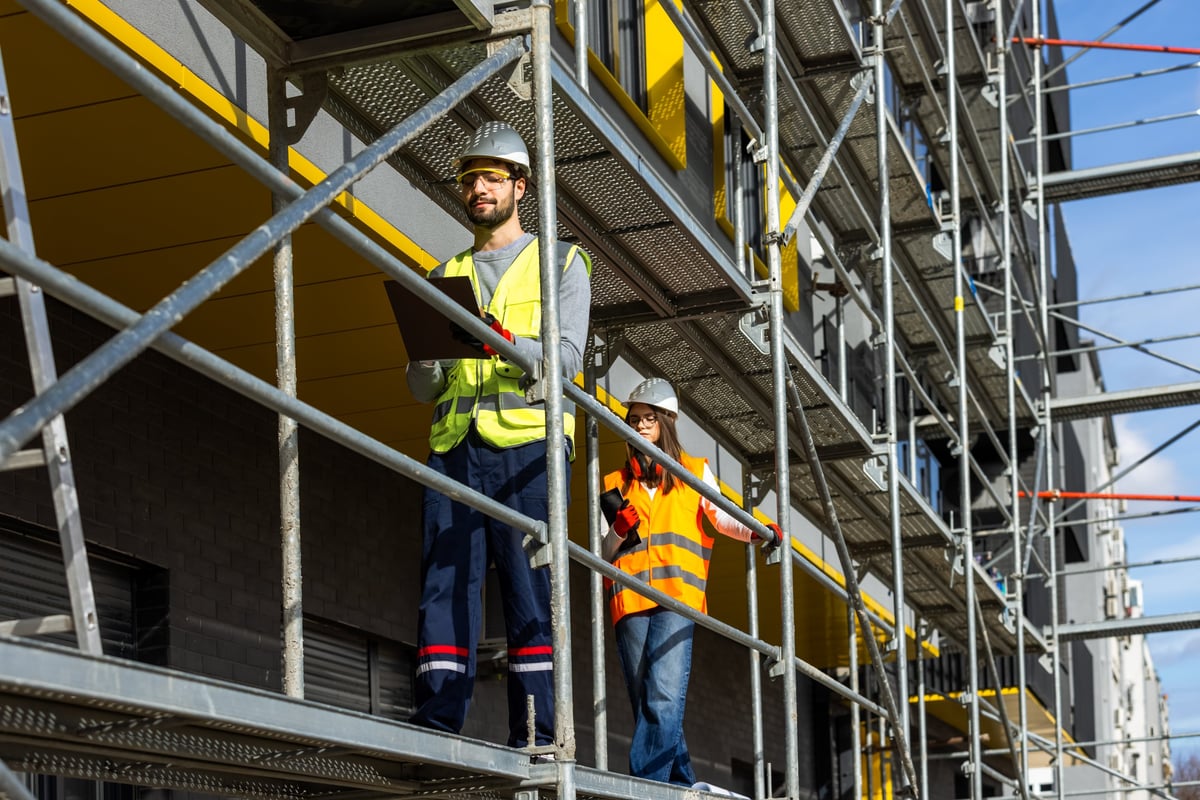 Professional engineers in safety gear surveying a commercial building project under construction